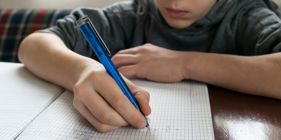 close up of young boy writing math into a notepad